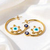 Raya gold plated open hoop earrings featuring blue and white enamel evil eye charms by Eda Jewels Dubai