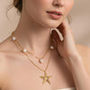 Sirena gold plated layered necklace featuring a textured starfish pendant and baroque freshwater pearls worn by a model by Eda Jewels Dubai.
