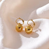 Ziva gold plated spherical ball drop earrings with leverback clasps resting on textured white fabric by Eda Jewels Dubai